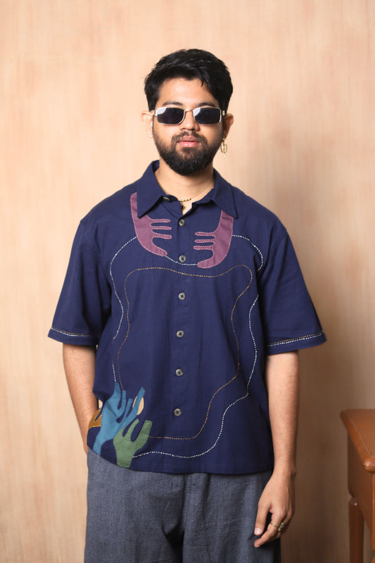 Man wearing a dark blue shirt with colorful designs against a beige background