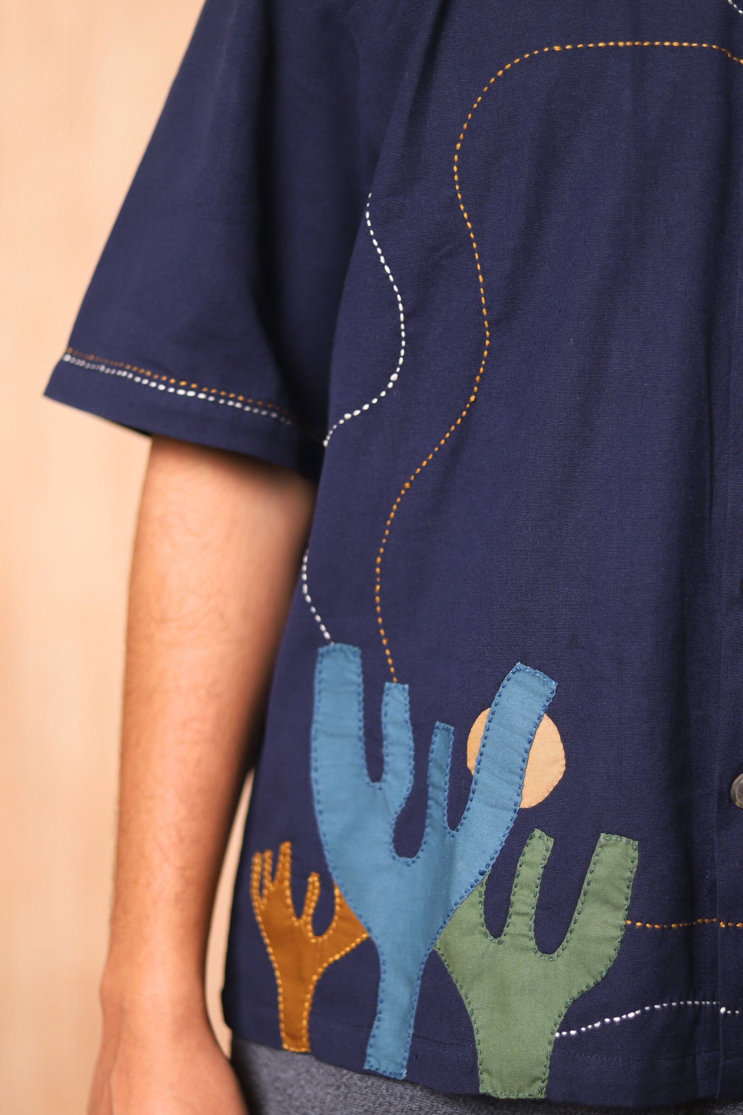 Navy blue shirt with colorful cactus designs on a beige background