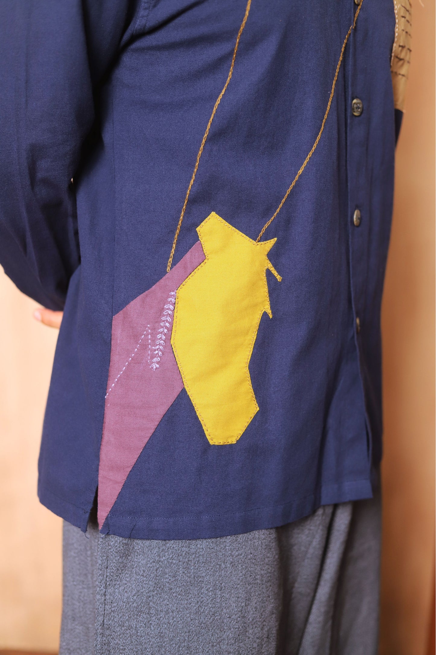 Navy blue shirt with a yellow and purple geometric design on a beige background