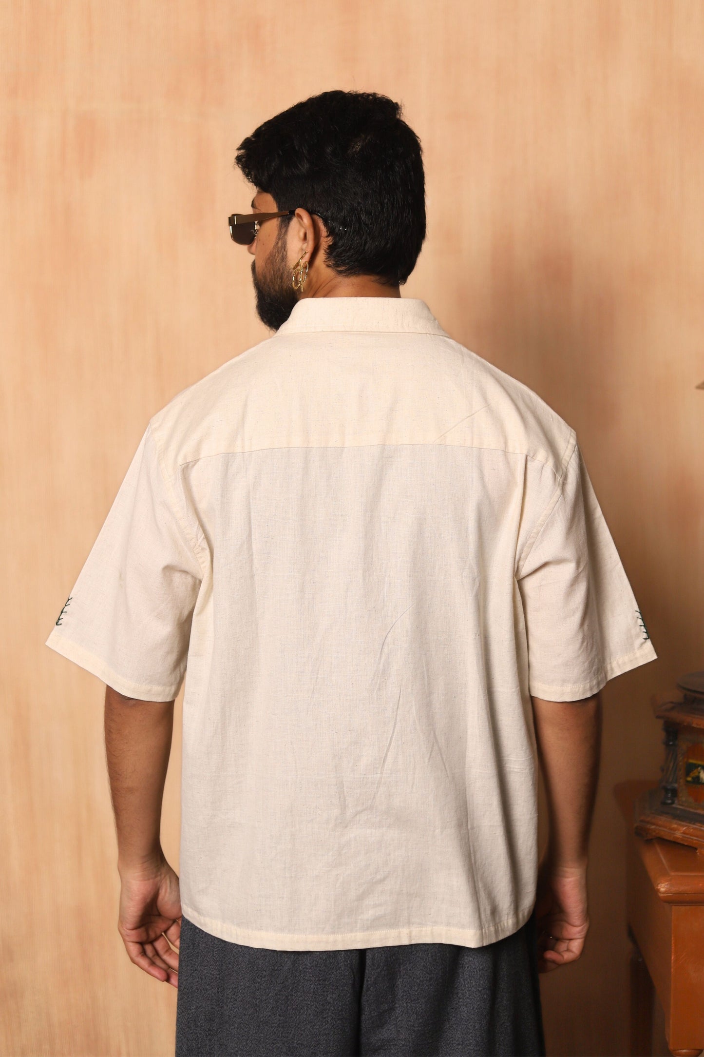 Man wearing a beige shirt against a beige wall