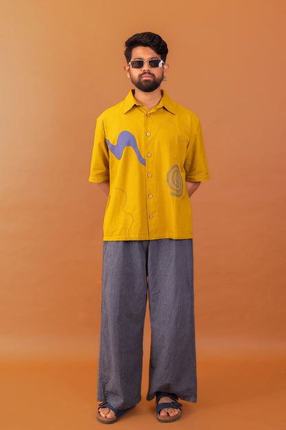 Man wearing a yellow shirt with graphic designs on an orange background