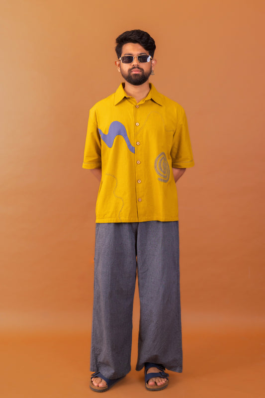 Man wearing a yellow shirt with graphic designs on an orange background