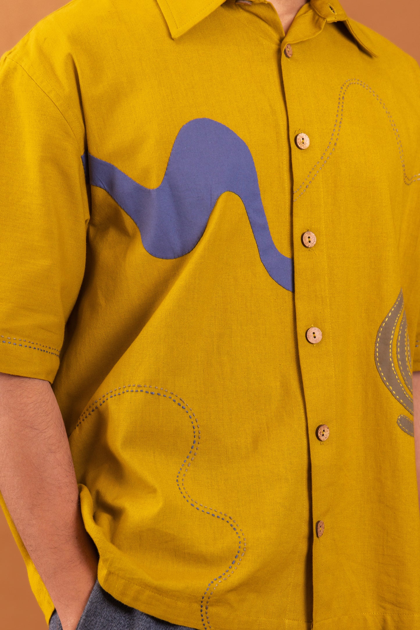 Yellow shirt with blue and gray designs on a brown background
