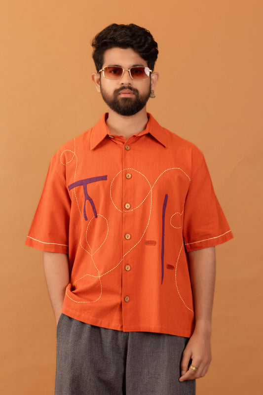 Man wearing an orange shirt with abstract designs on a brown background