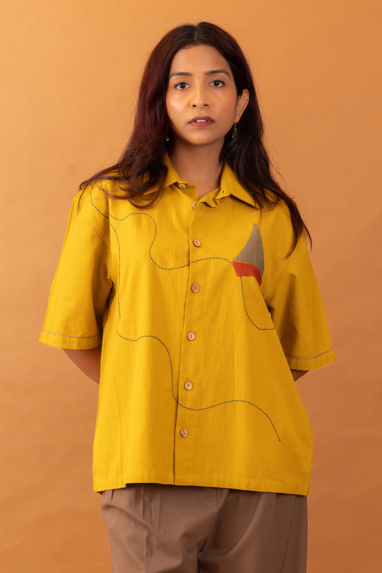 Woman wearing a yellow shirt with a brown background