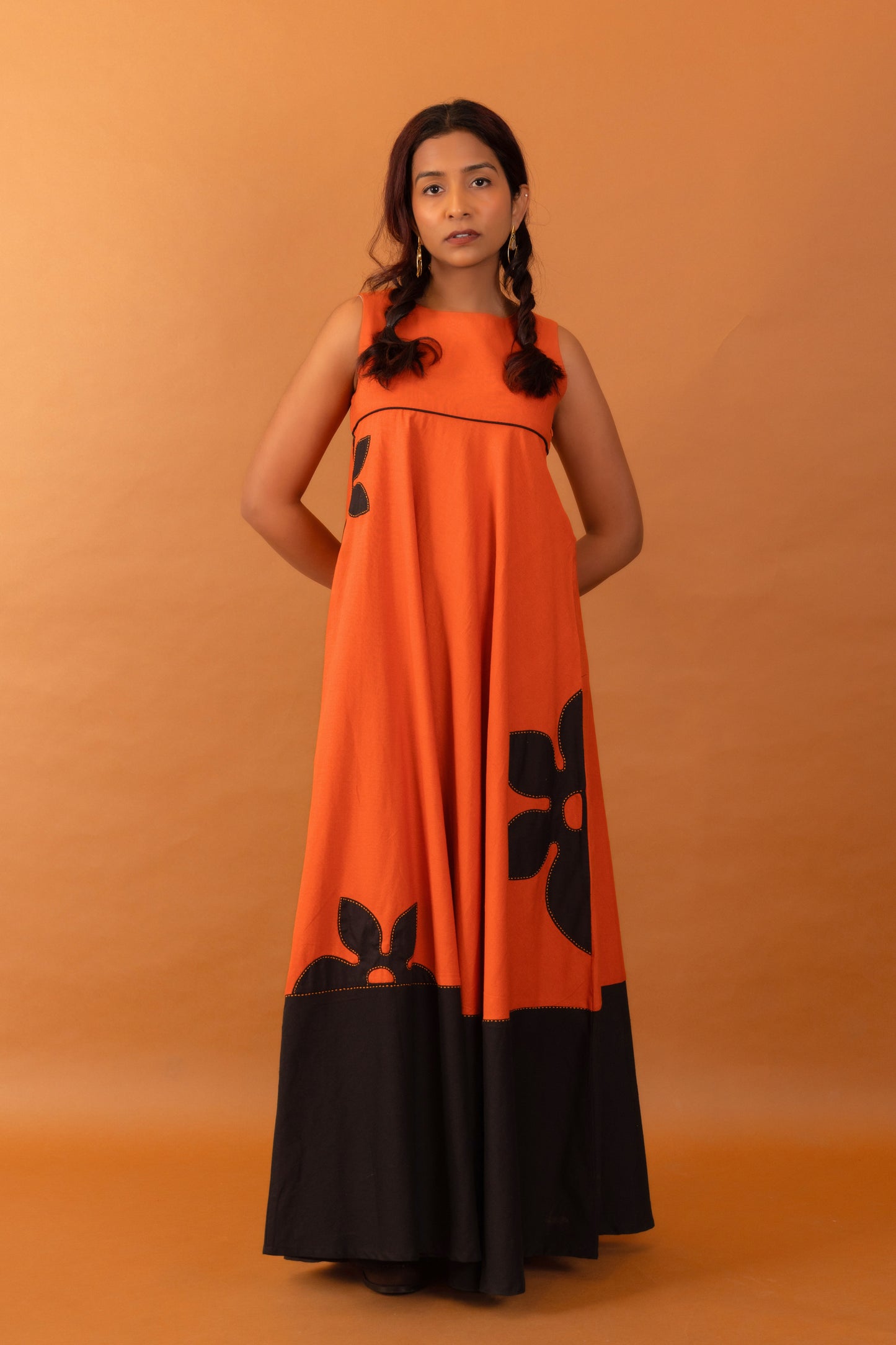 Woman wearing an orange and black dress against an orange background