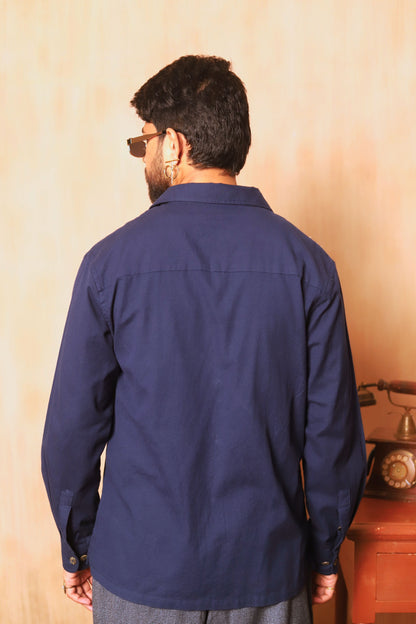 Man wearing a navy blue shirt from behind with a beige wall background