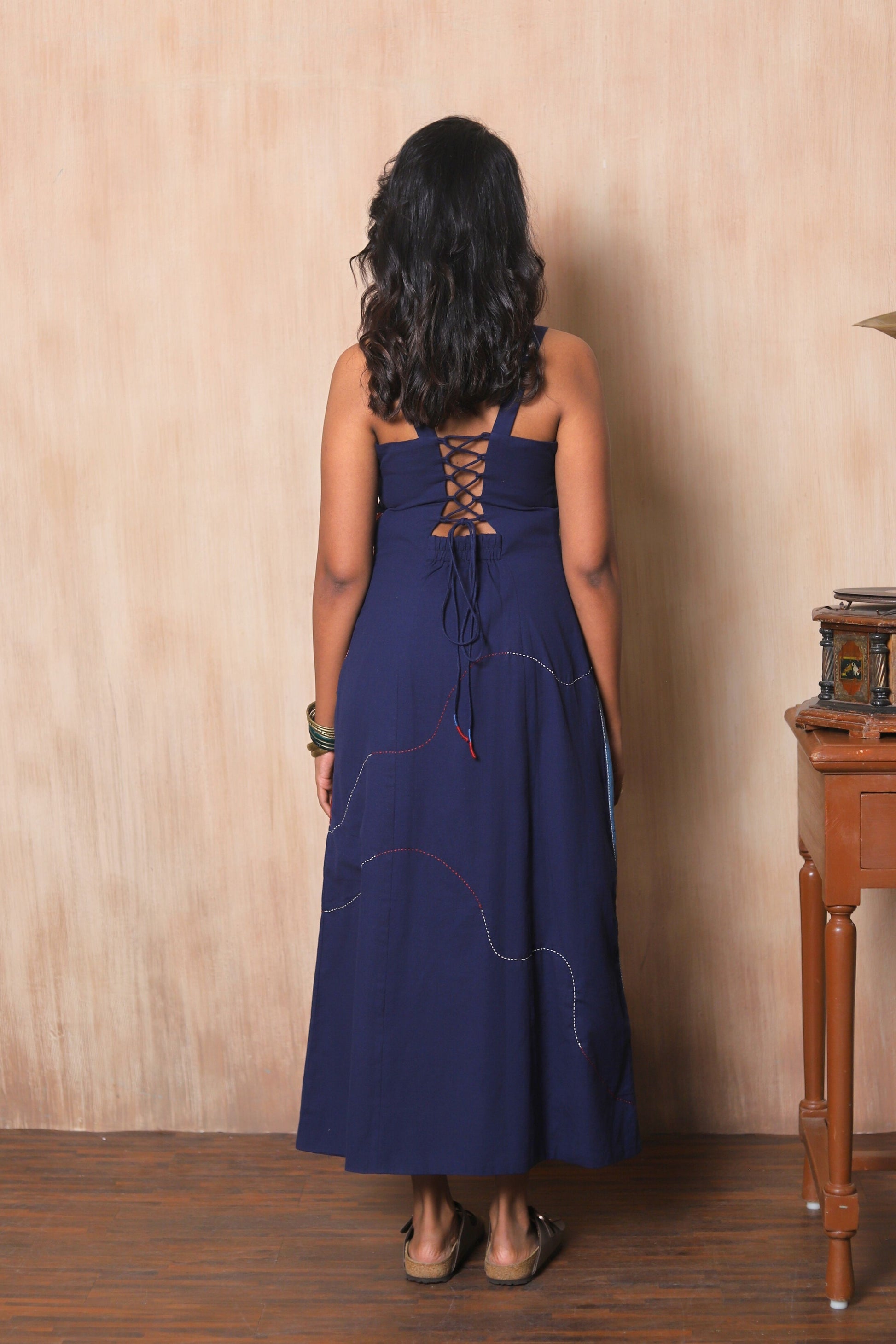 Woman wearing a blue dress with lace-up back.